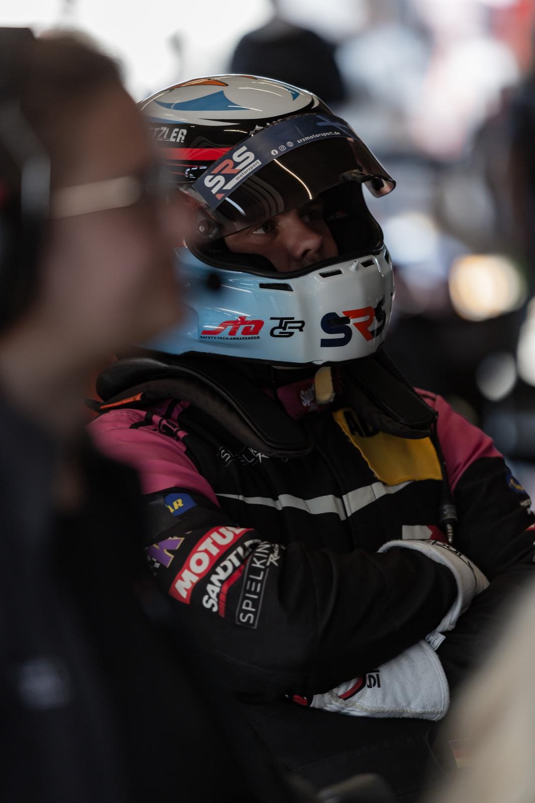 Driver in race suit and helmet in the pit box before going out